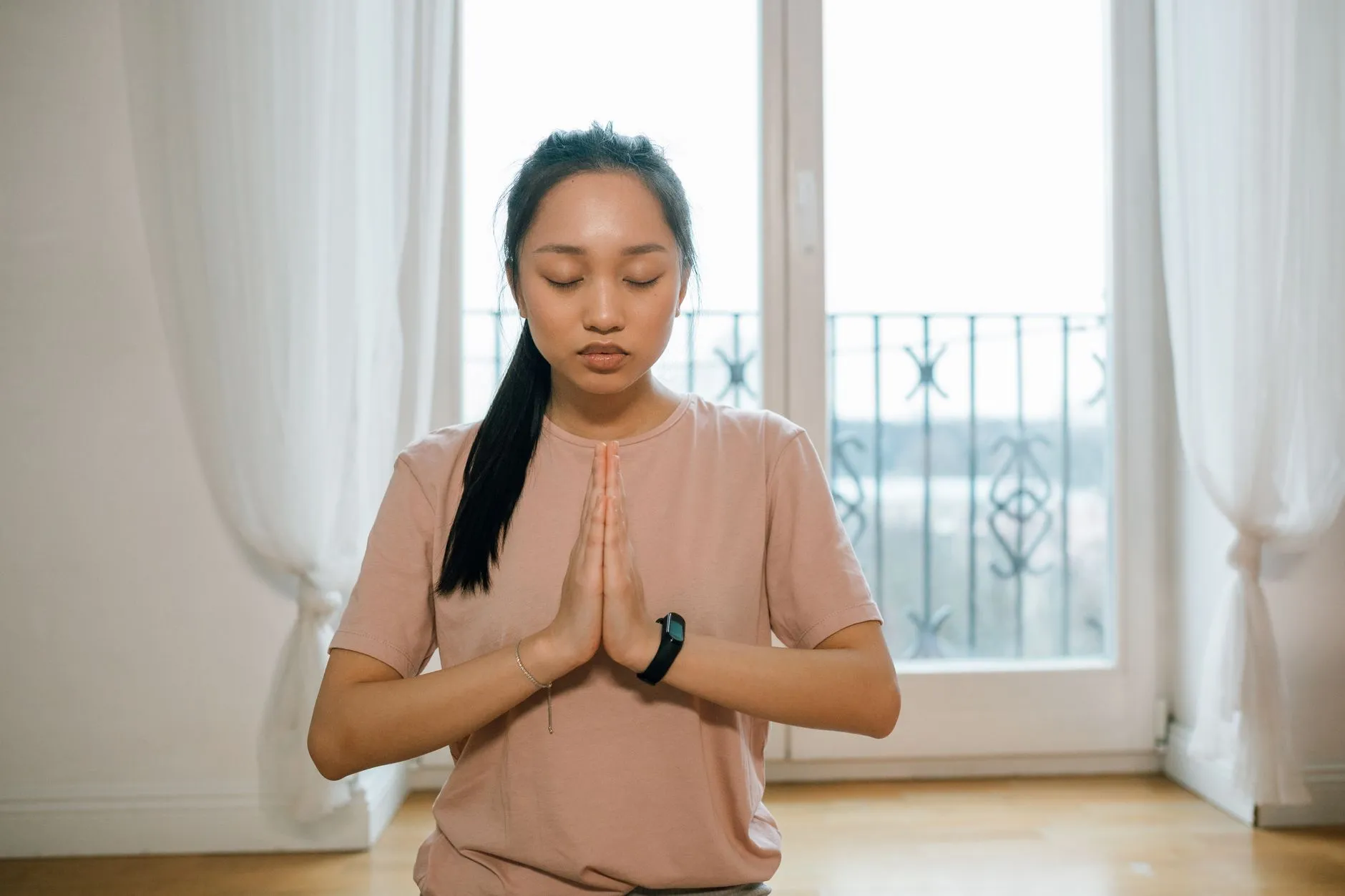 Person sitting calmly by a window, practising slow breathing with eyes closed