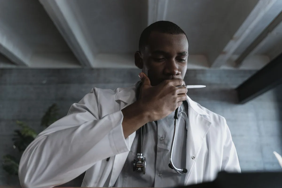 Doctor in a white coat pausing in a thoughtful, reflective moment