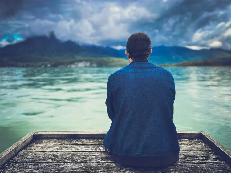 Person looking out over calm water, representing calm and clarity with effective anxiety therapy online